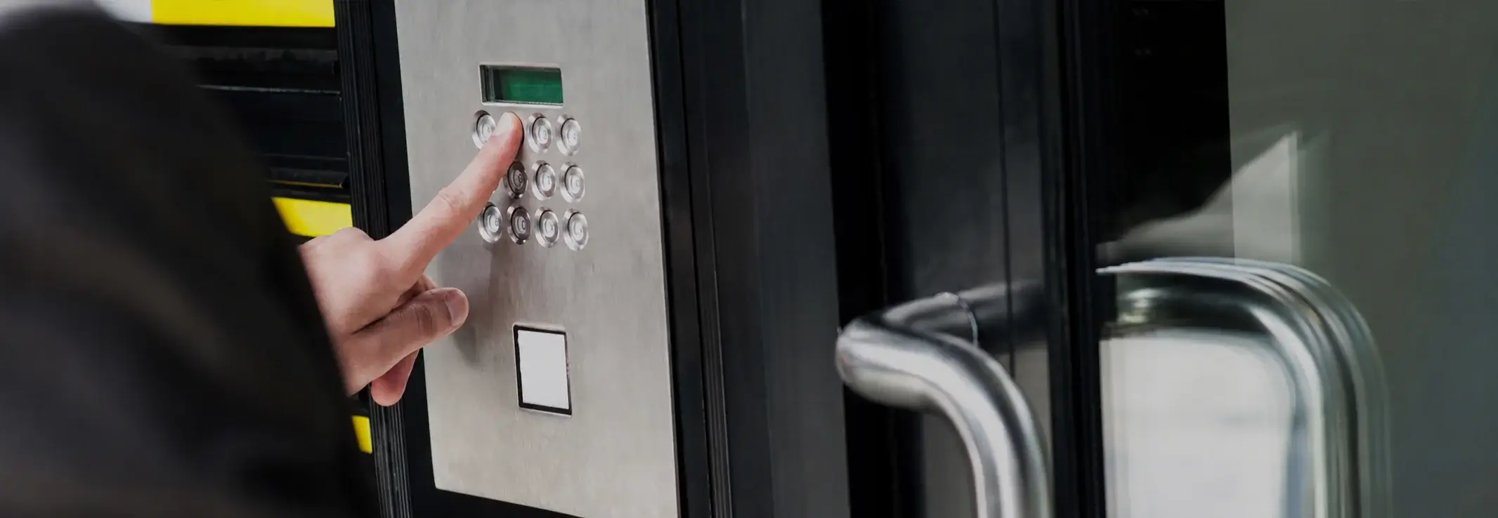 Finger pressing keypad on security door panel.